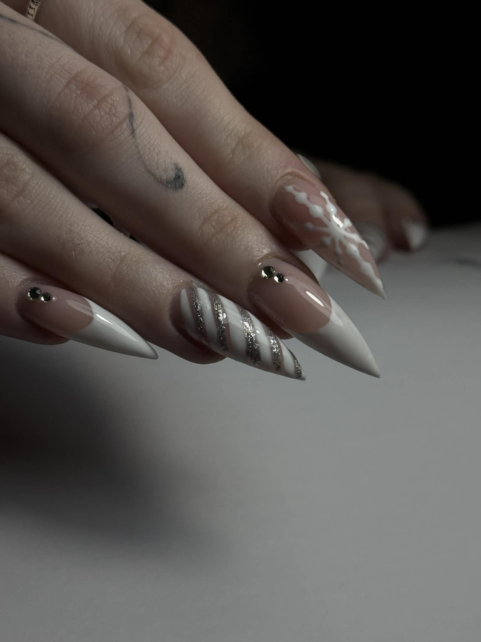 A white and nude stiletto set with a hand painted snowflake, candy cane stripes and black stones